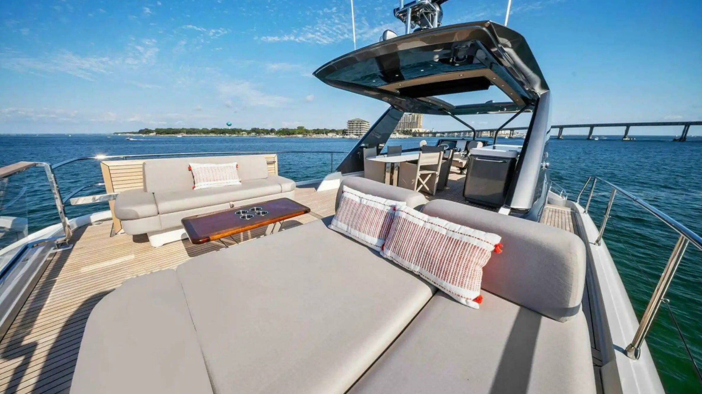 Luxury yacht deck with sofas, table, and ocean view under blue sky.