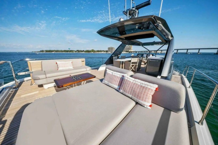Luxury yacht deck with sofas, table, and ocean view under blue sky.