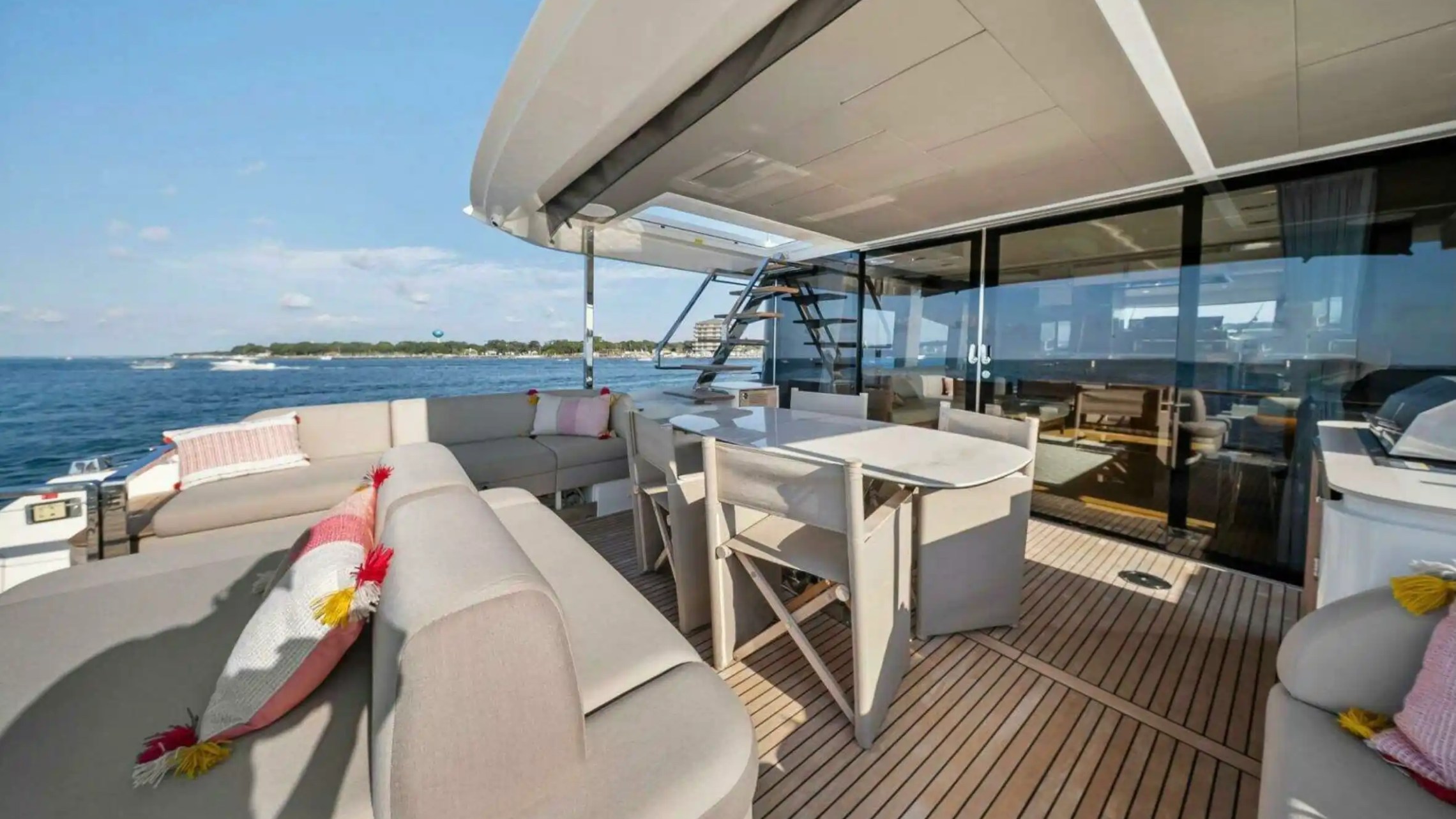 Luxury yacht deck with sofas and dining table overlooking the ocean.