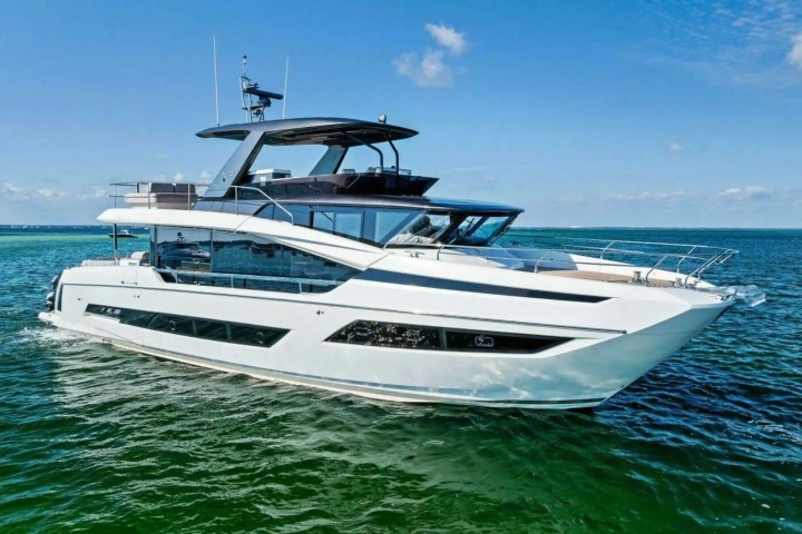White luxury yacht cruising on calm blue sea under a clear sky.