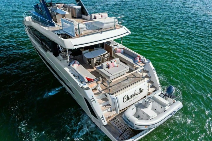 Luxurious yacht with multiple decks cruising through green ocean waters.