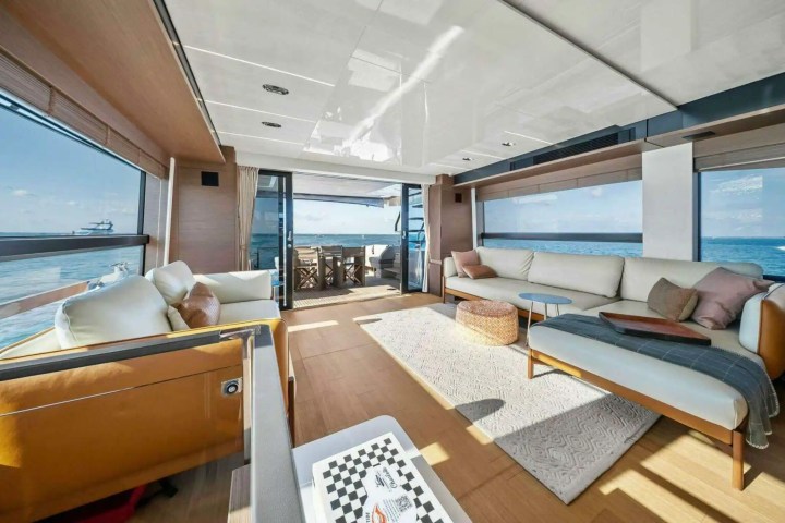 Spacious yacht interior with sofas, large windows, and ocean view.