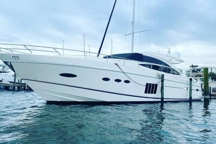 White yacht docked on calm water with overcast sky in the background.