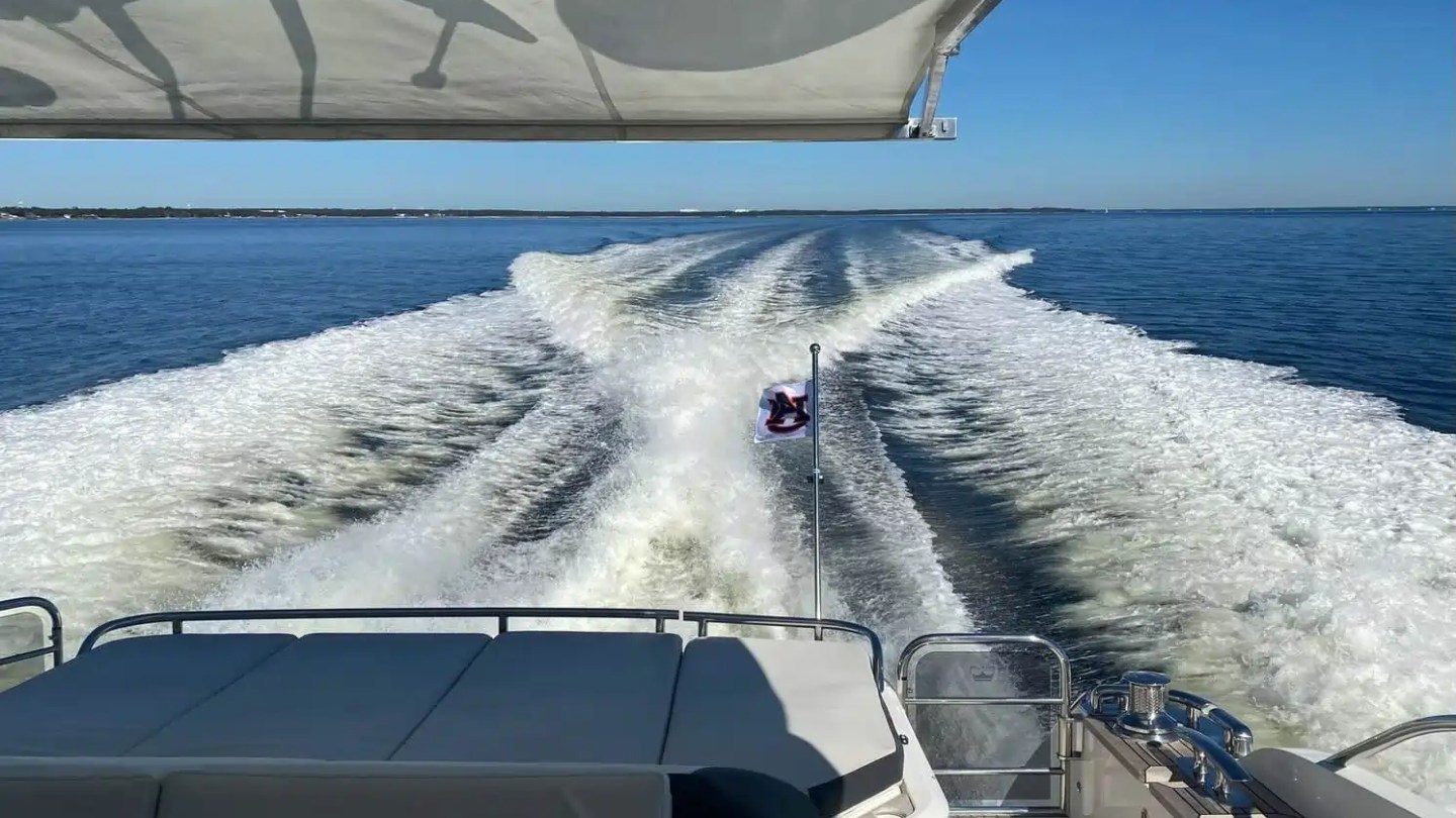 View from a boat's deck showing wake trail on a sunny day