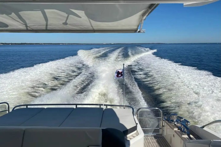 View from a boat's deck showing wake trail on a sunny day