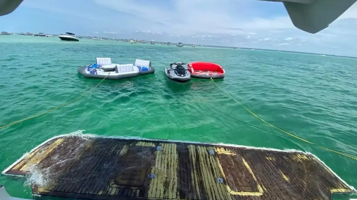 Inflatable chairs and a jet ski floating on turquoise water, viewed from a boat's platform.