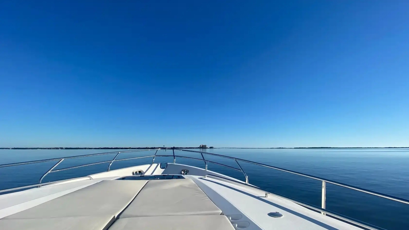 Bow of a boat on calm water under a clear blue sky.