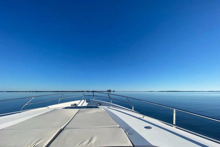 Bow of a boat on calm water under a clear blue sky.