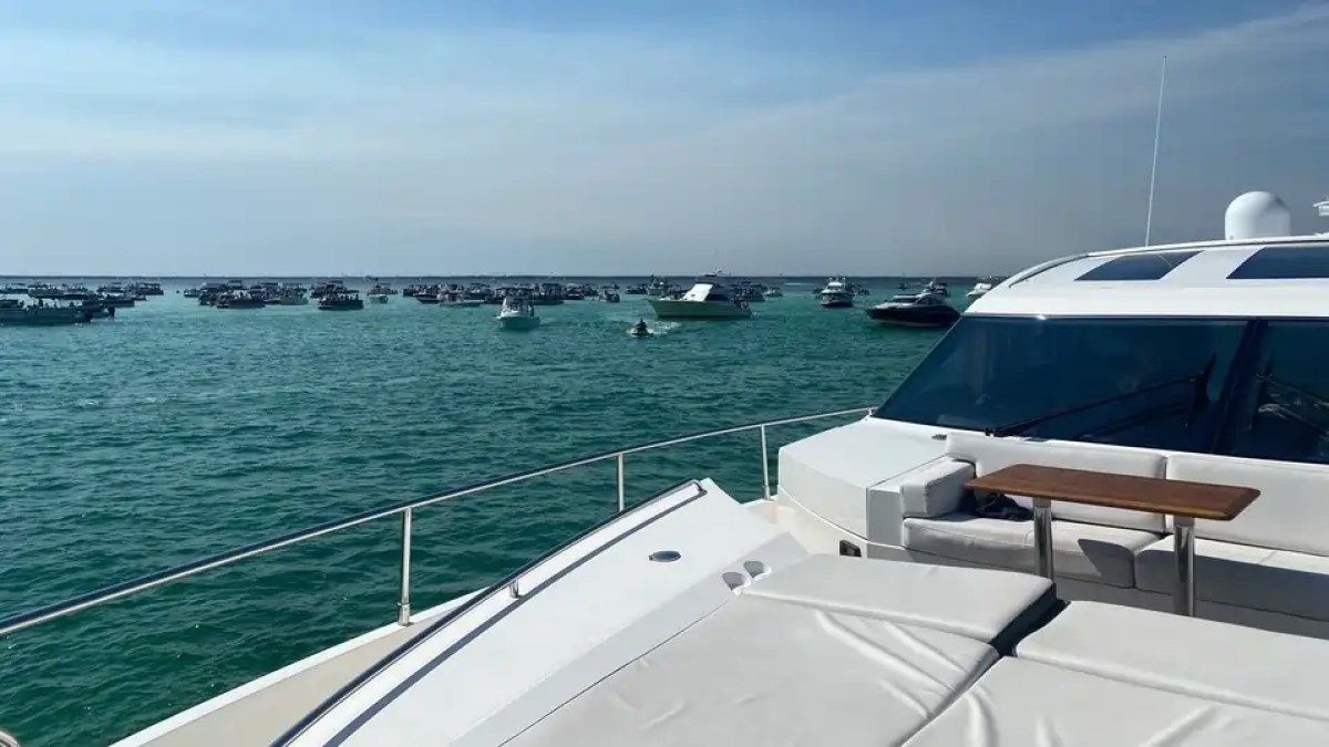 View from a yacht deck with numerous boats on a sunny ocean day.