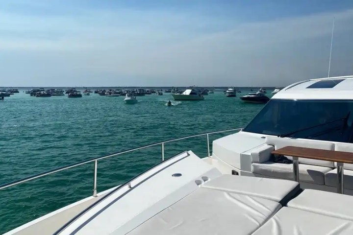 View from a yacht deck with numerous boats on a sunny ocean day.