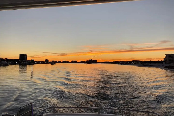 Sunset view from a boat, with buildings outlined against an orange sky.