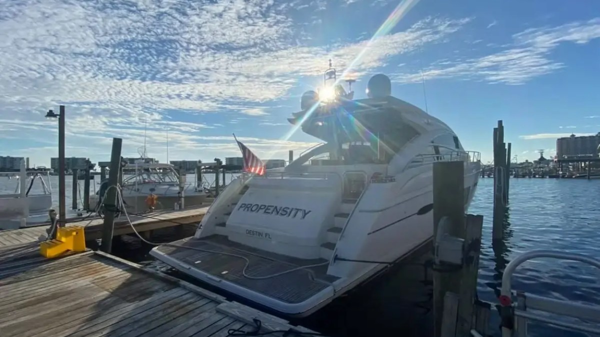 A yacht named 'Propensity' docked at a pier with sunny weather and a partly cloudy sky.