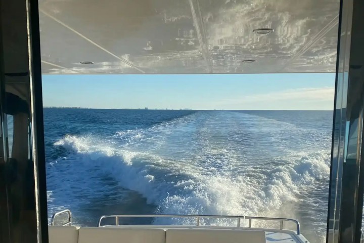 View from boat interior of ocean waves and horizon under clear sky.