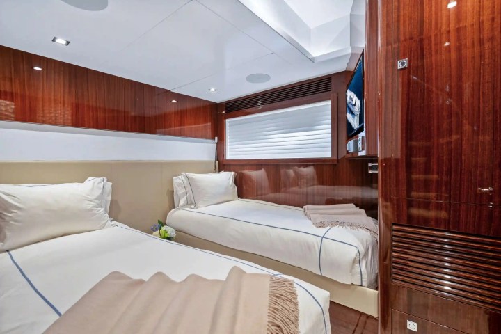 Luxurious cabin with two twin beds, wood paneling, and a window.