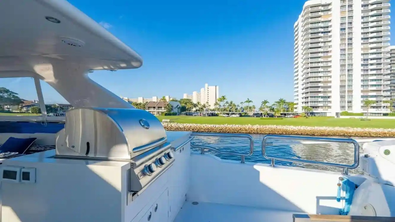 Luxury yacht outdoor grill with ocean view and high-rise buildings in background.