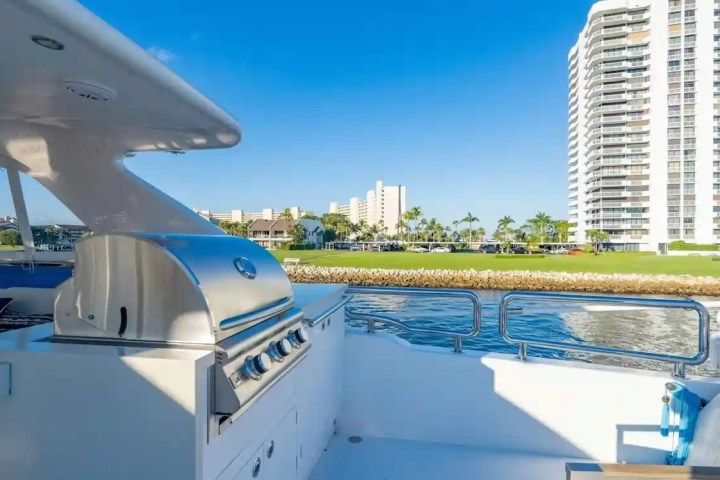 Luxury yacht outdoor grill with ocean view and high-rise buildings in background.