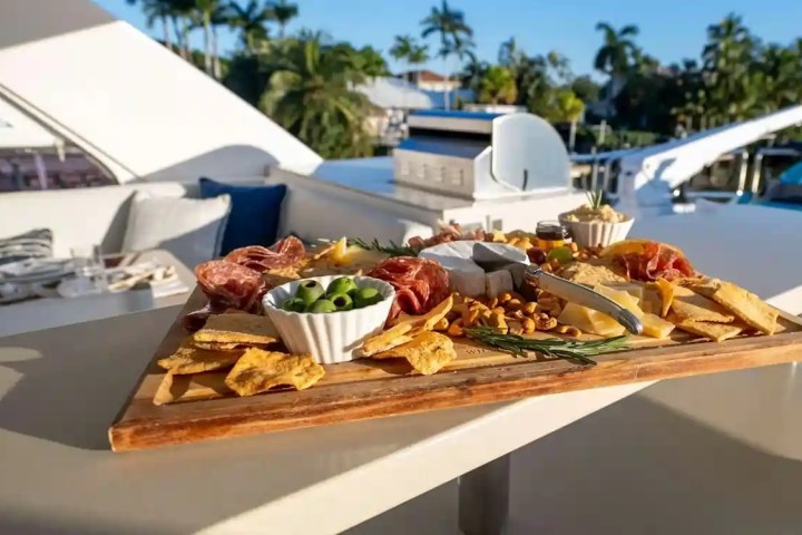 Cheese and charcuterie board on yacht deck with scenic background.