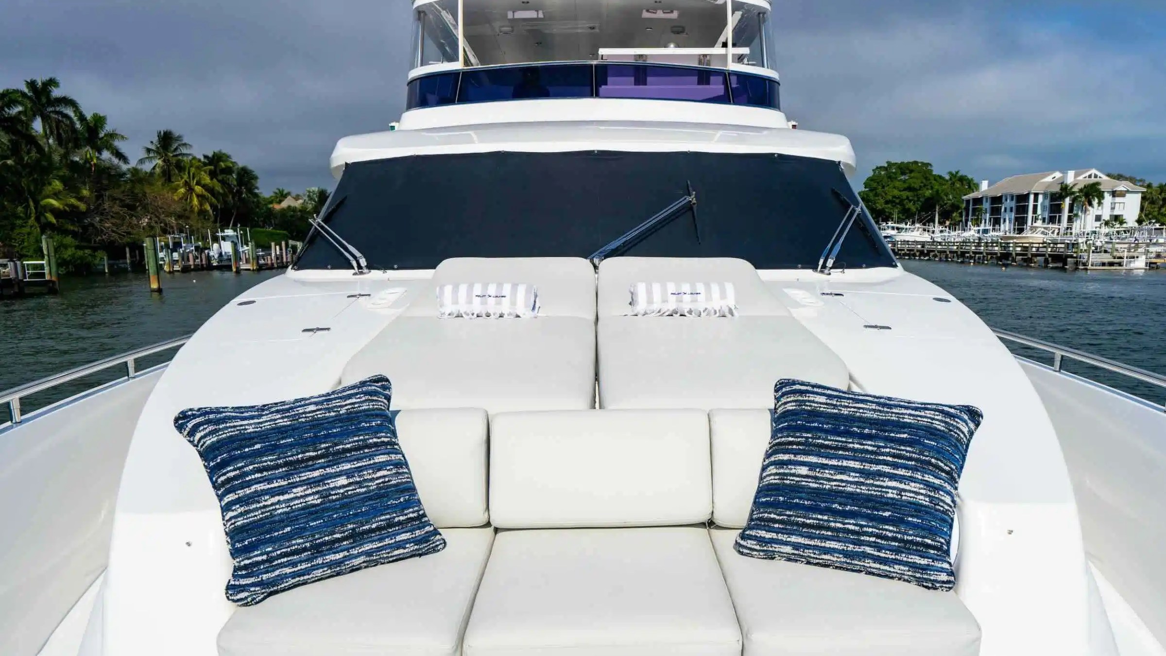 Luxury yacht deck with striped cushions and pillows, overlooking a marina.