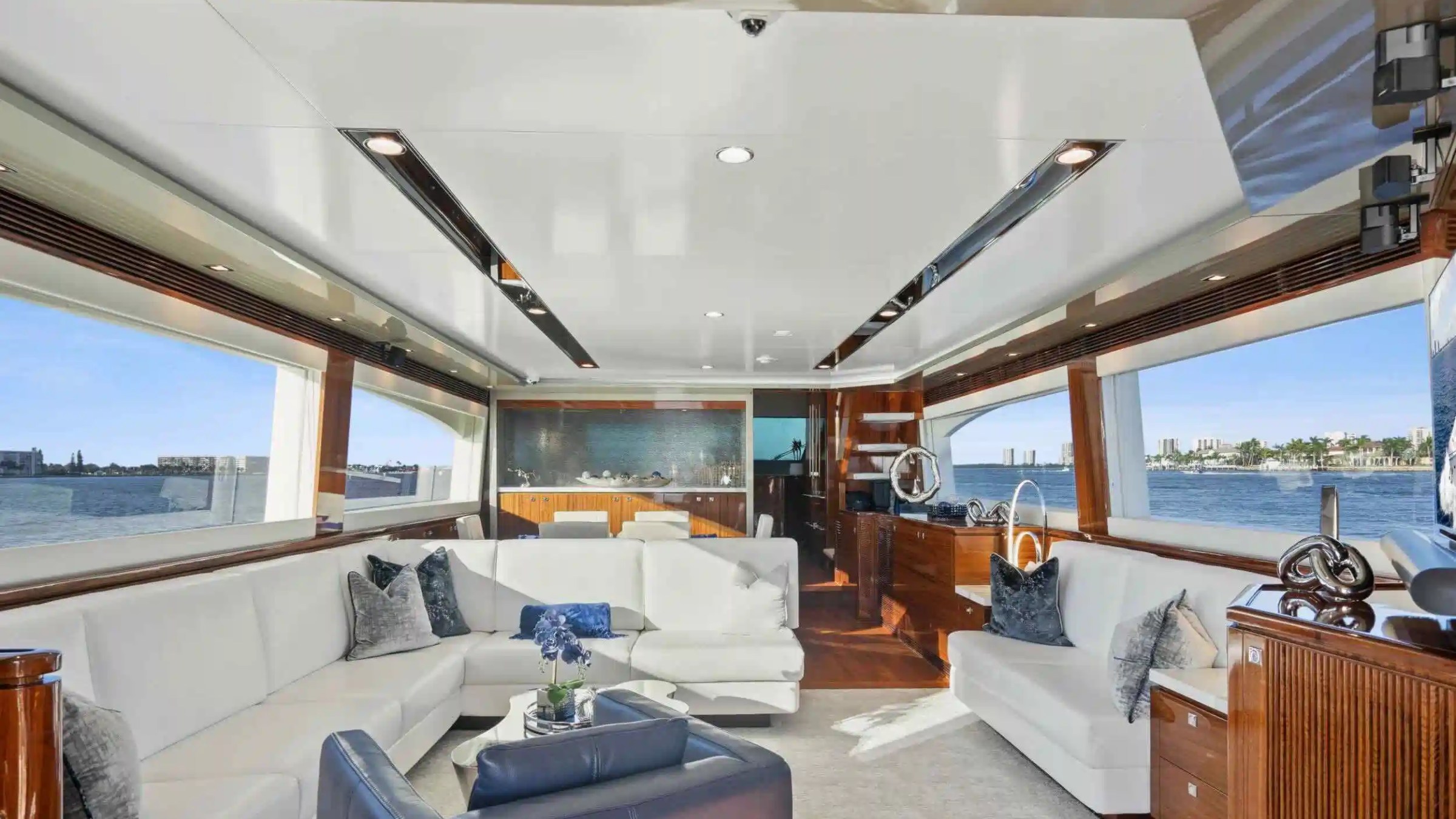 Luxurious yacht interior with white sofas, panoramic windows, and elegant decor overlooking the sea.
