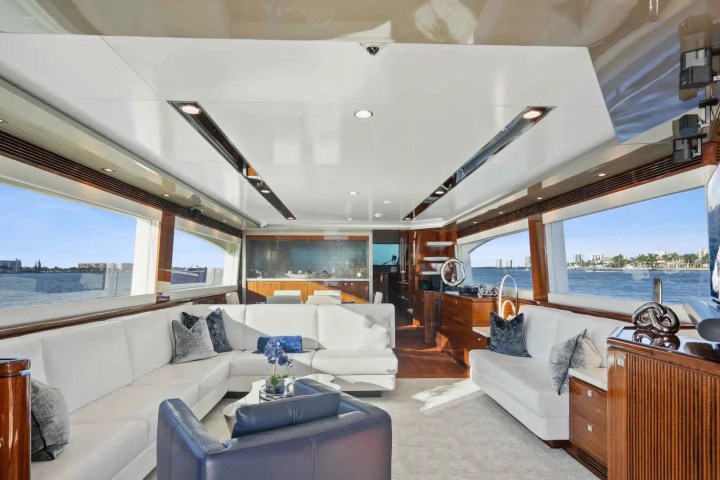 Luxurious yacht interior with white sofas, panoramic windows, and elegant decor overlooking the sea.