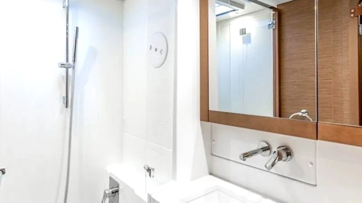 Modern bathroom with a shower, white surface, and mirrored cabinet over sink.