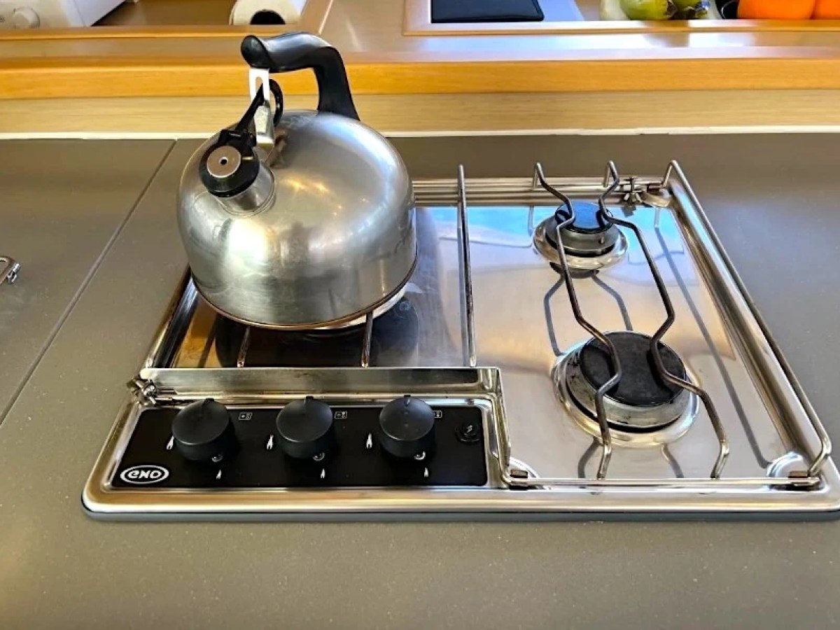 Metal kettle on a gas stovetop with two burners and control knobs.
