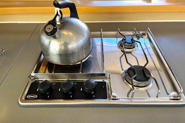 Metal kettle on a gas stovetop with two burners and control knobs.