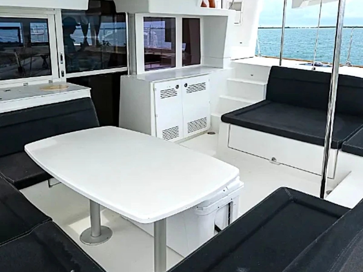 Interior of a yacht's deck with white table, black seating, and ocean view.