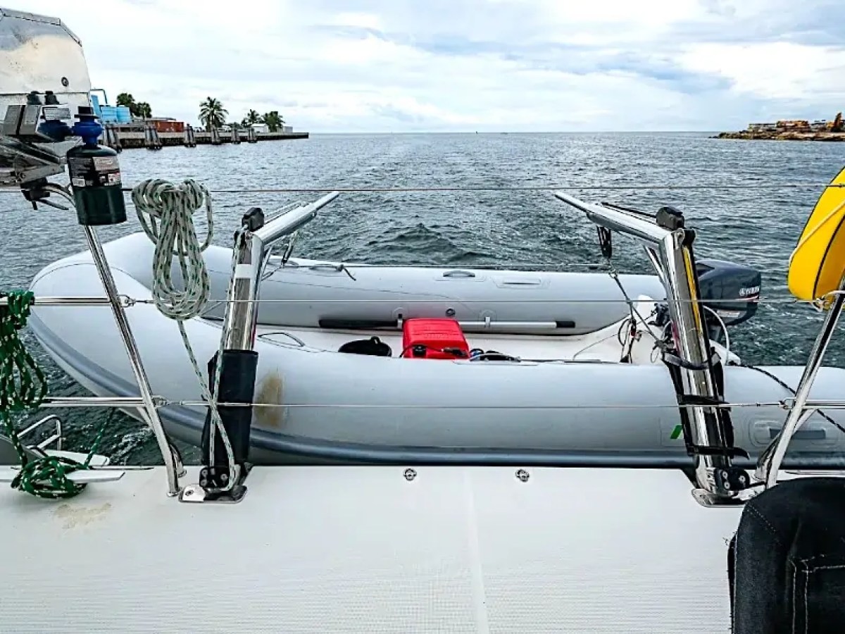 Inflatable dinghy secured on yacht deck with sea view and coast in background.