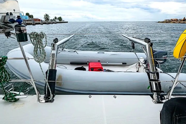 Inflatable dinghy secured on yacht deck with sea view and coast in background.