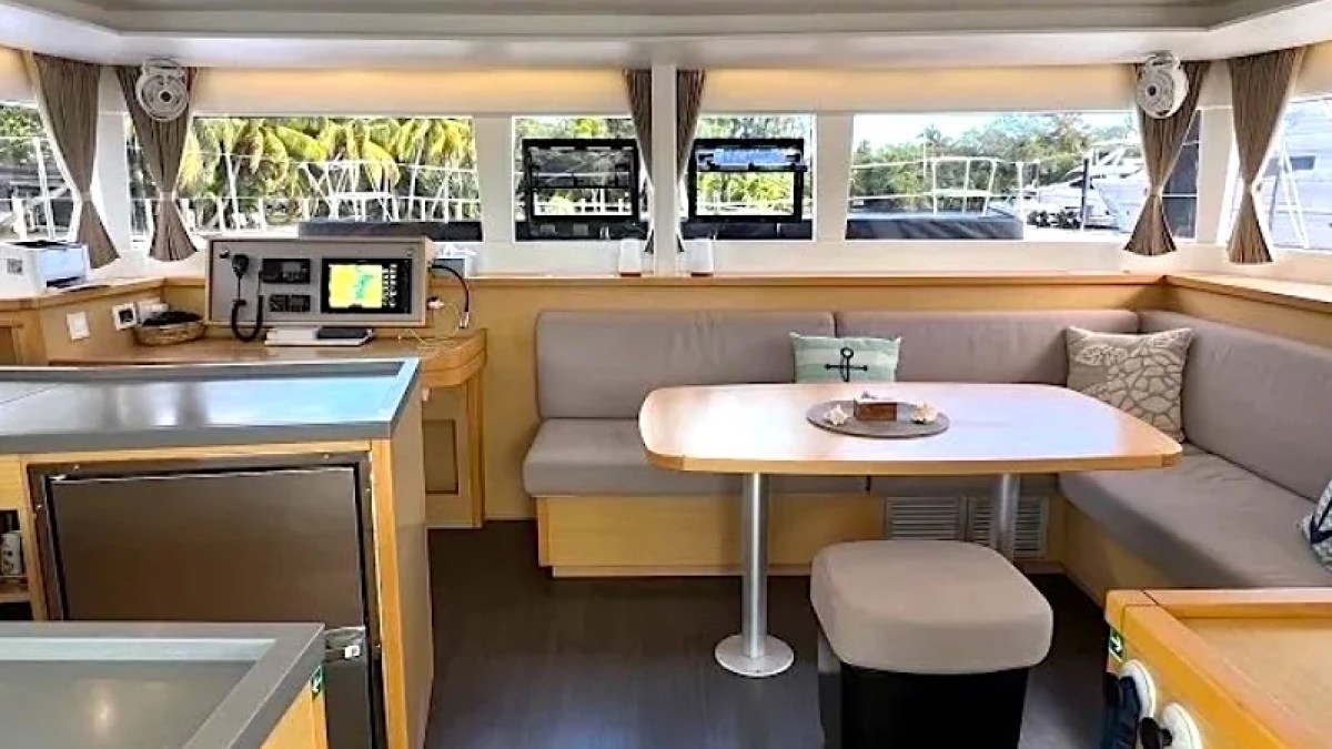 Interior of a modern boat with seating area, table, and navigation equipment.