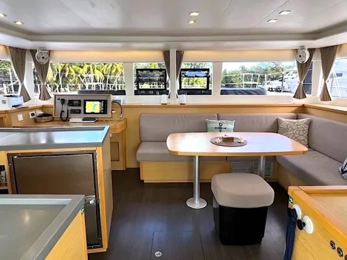 Interior of a modern boat with seating area, table, and navigation equipment.