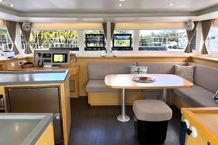 Interior of a modern boat with seating area, table, and navigation equipment.