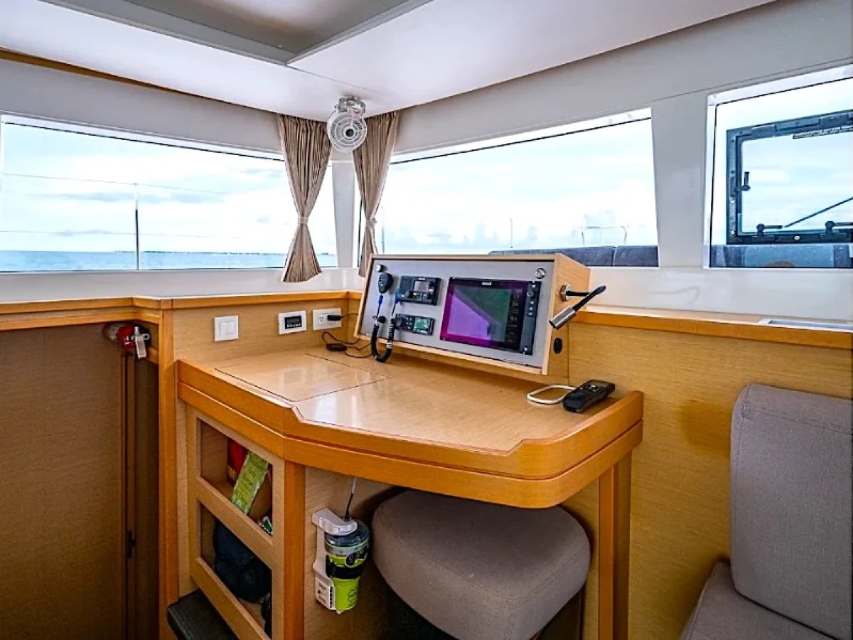 Boat interior with navigation desk, screens, and large windows overlooking the ocean.