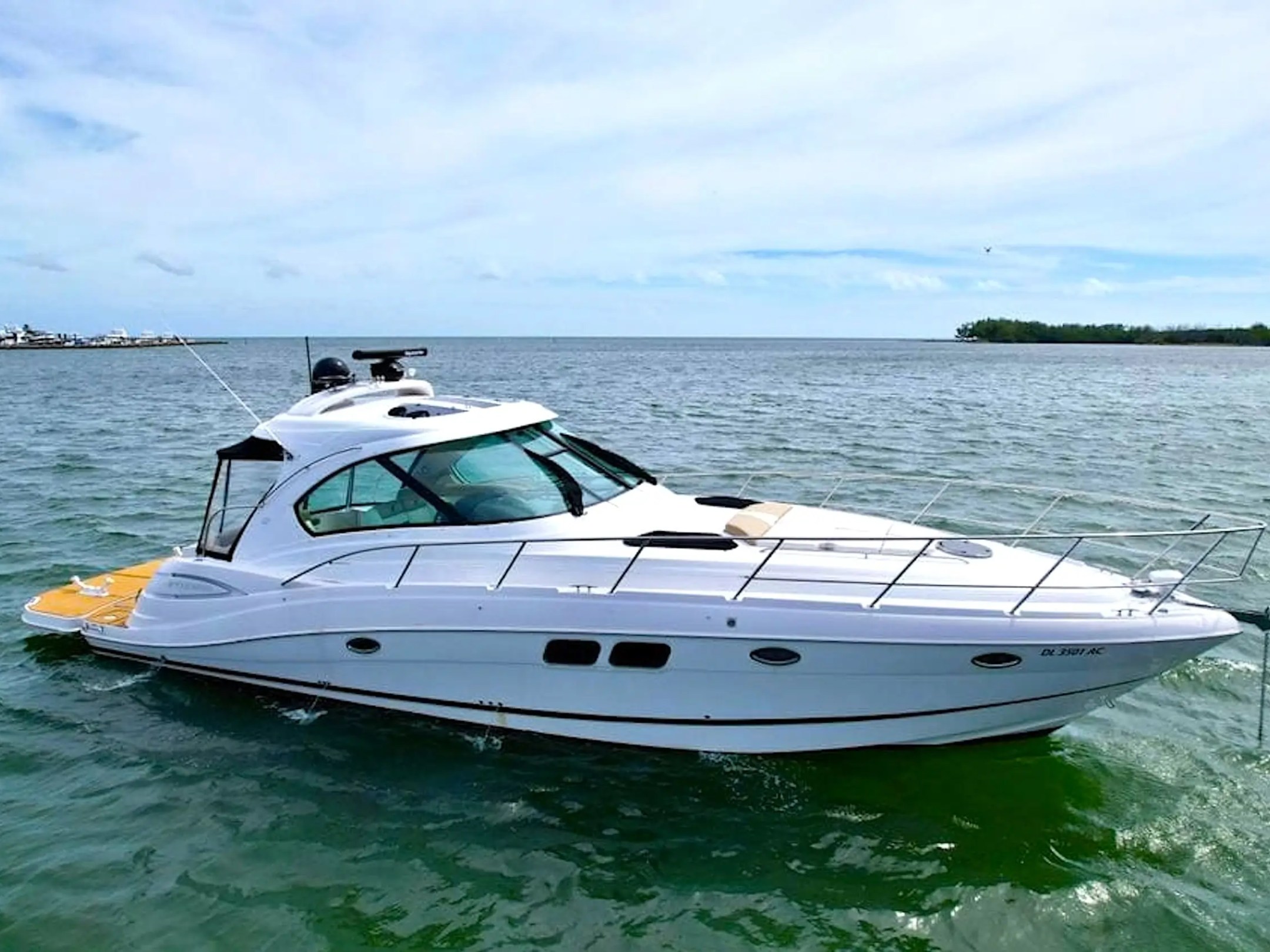 White motorboat on green water with a clear sky in the background.