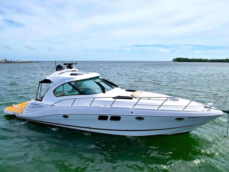 White motorboat on green water with a clear sky in the background.