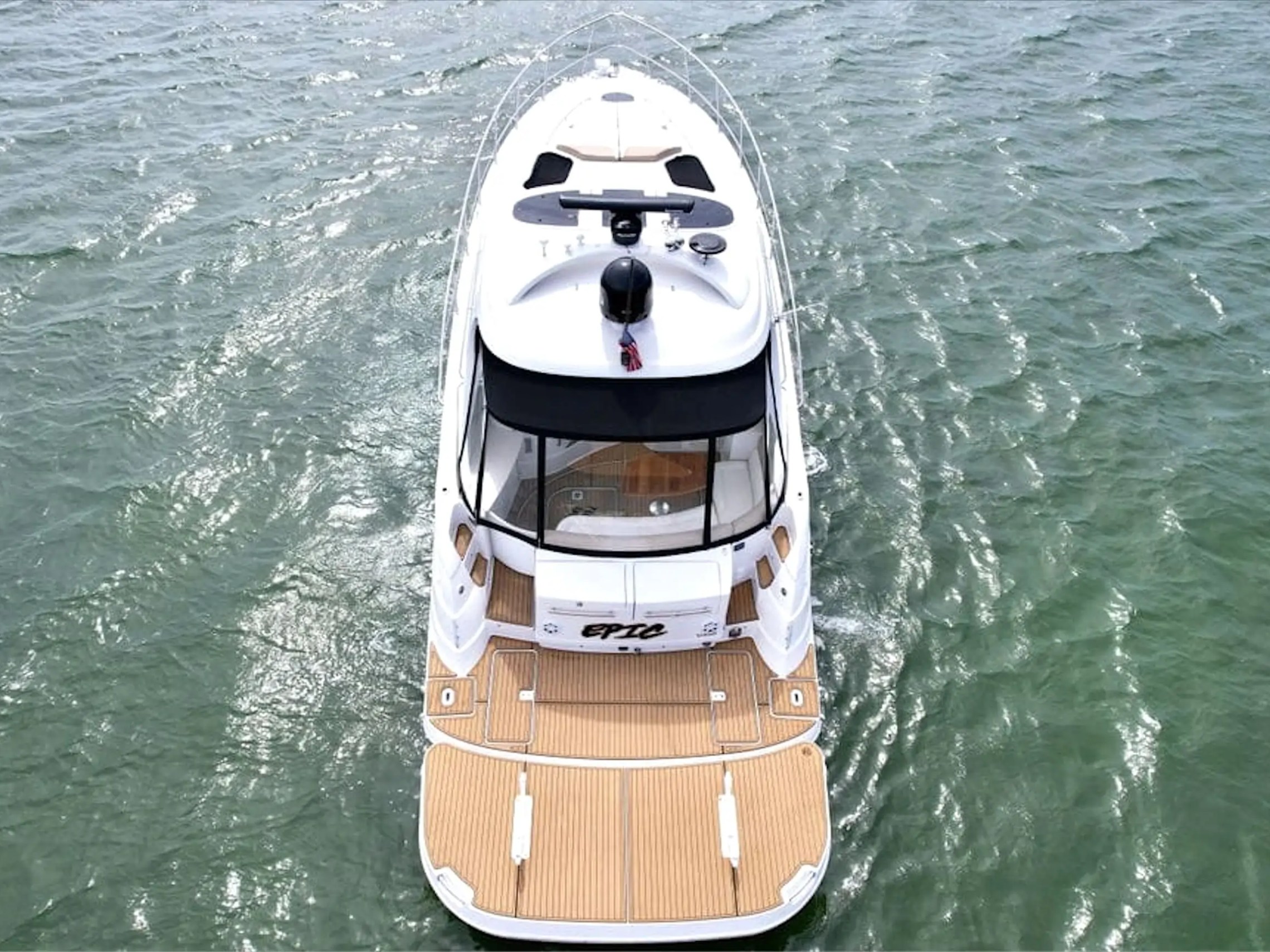 Top view of a white yacht on green ocean water.