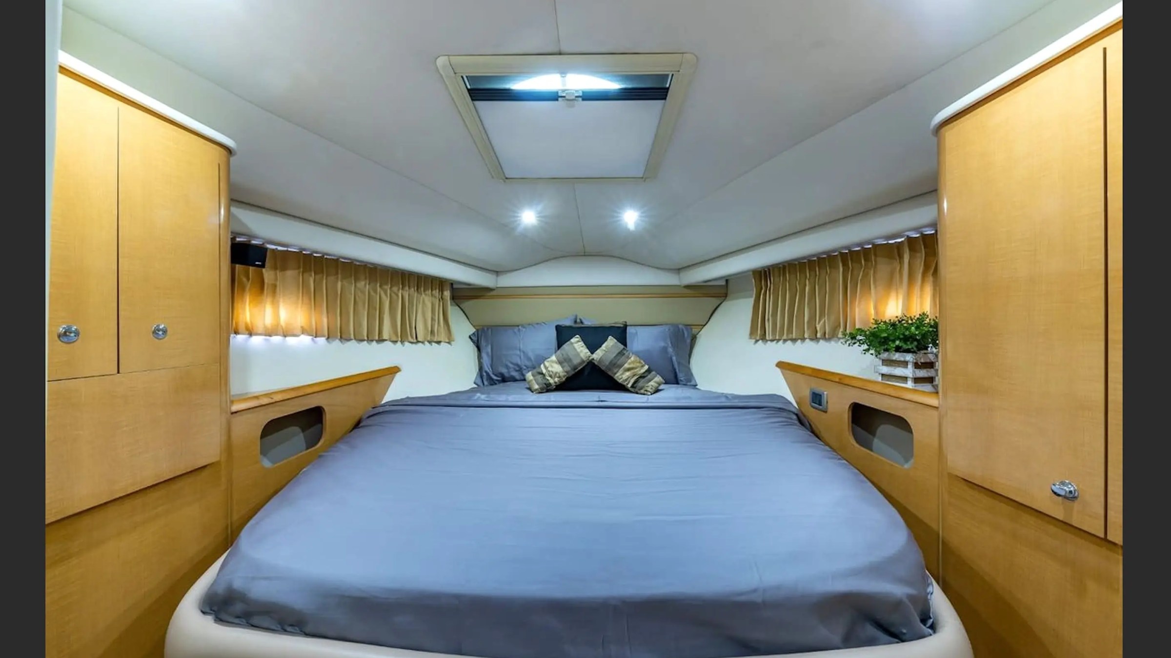 Cozy bedroom in a boat cabin with a double bed and wooden cabinets on each side.