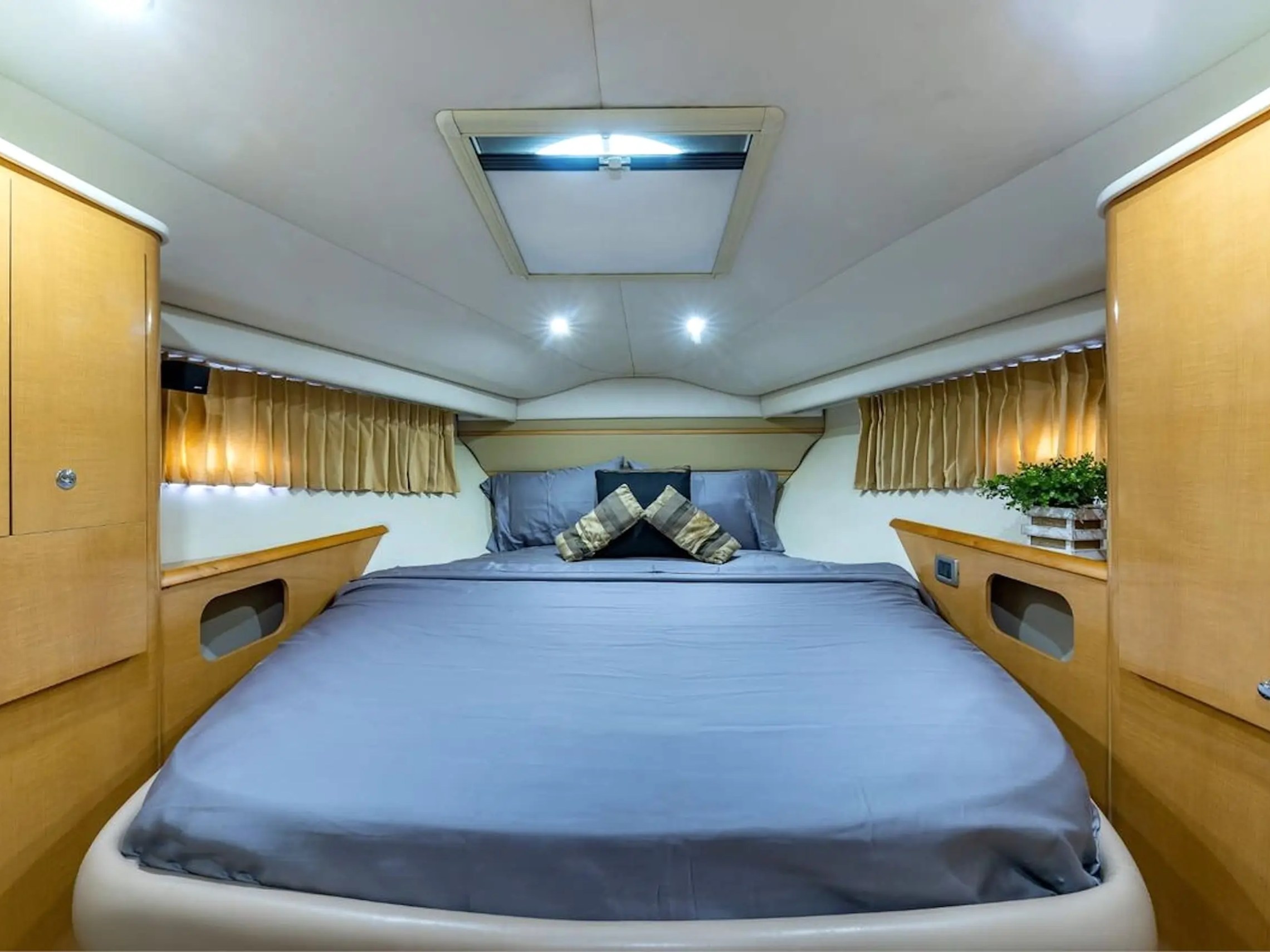 Cozy bedroom in a boat cabin with a double bed and wooden cabinets on each side.