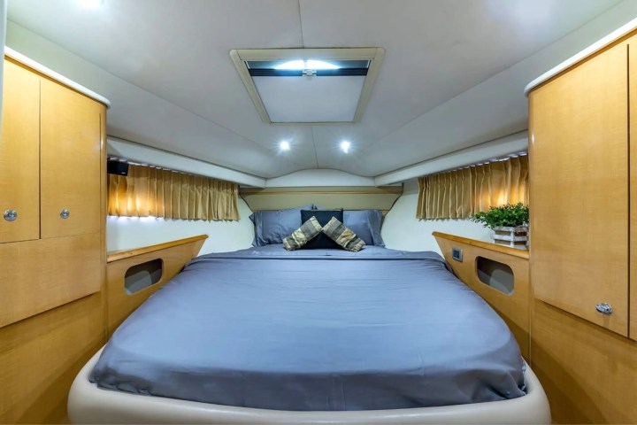 Cozy bedroom in a boat cabin with a double bed and wooden cabinets on each side.
