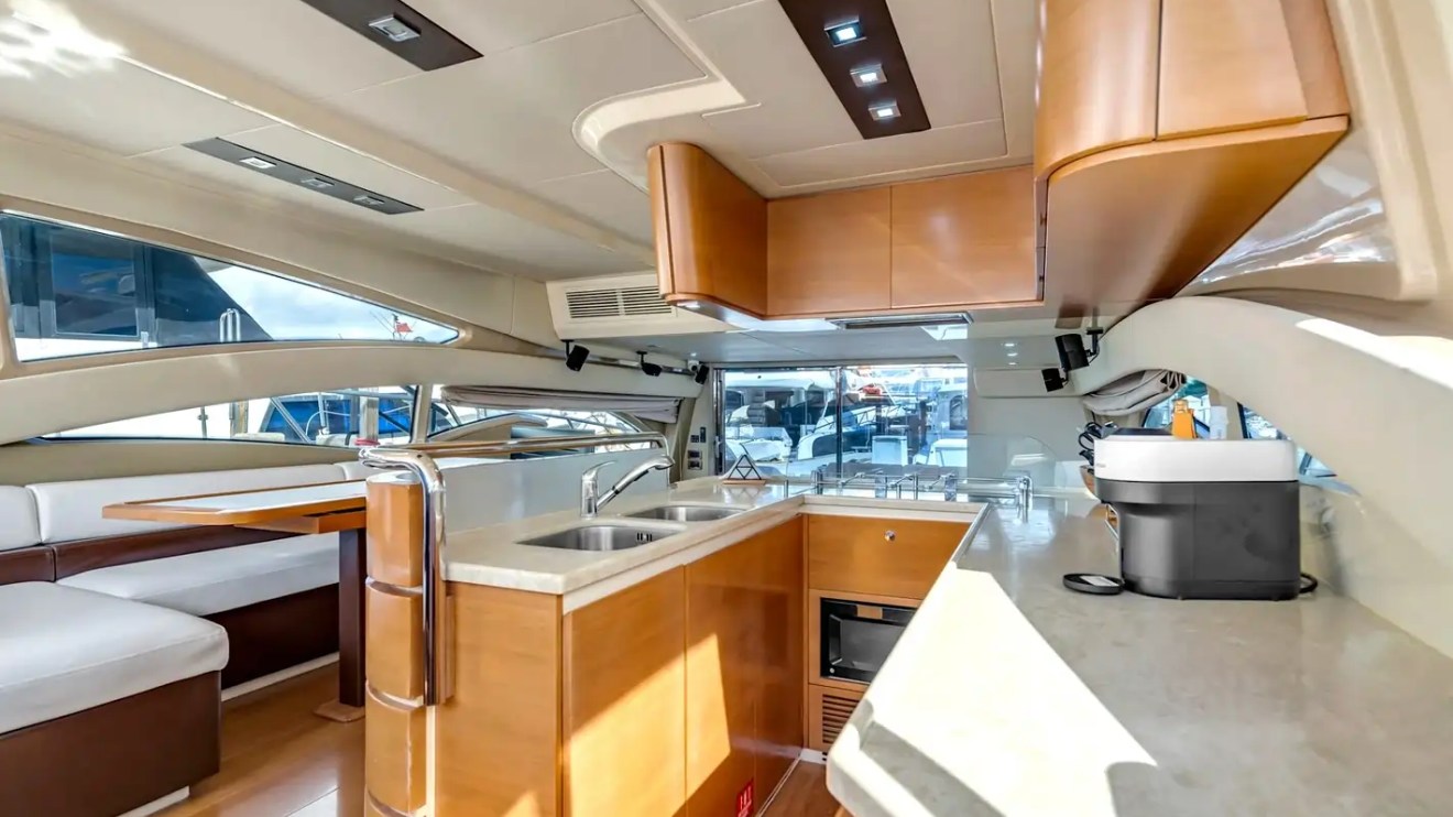 Luxurious yacht interior with kitchen, seating area, wooden cabinets, and large windows.