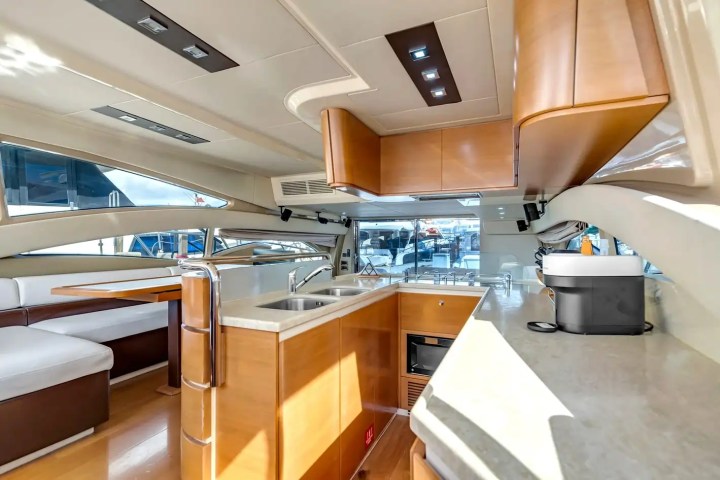 Luxurious yacht interior with kitchen, seating area, wooden cabinets, and large windows.