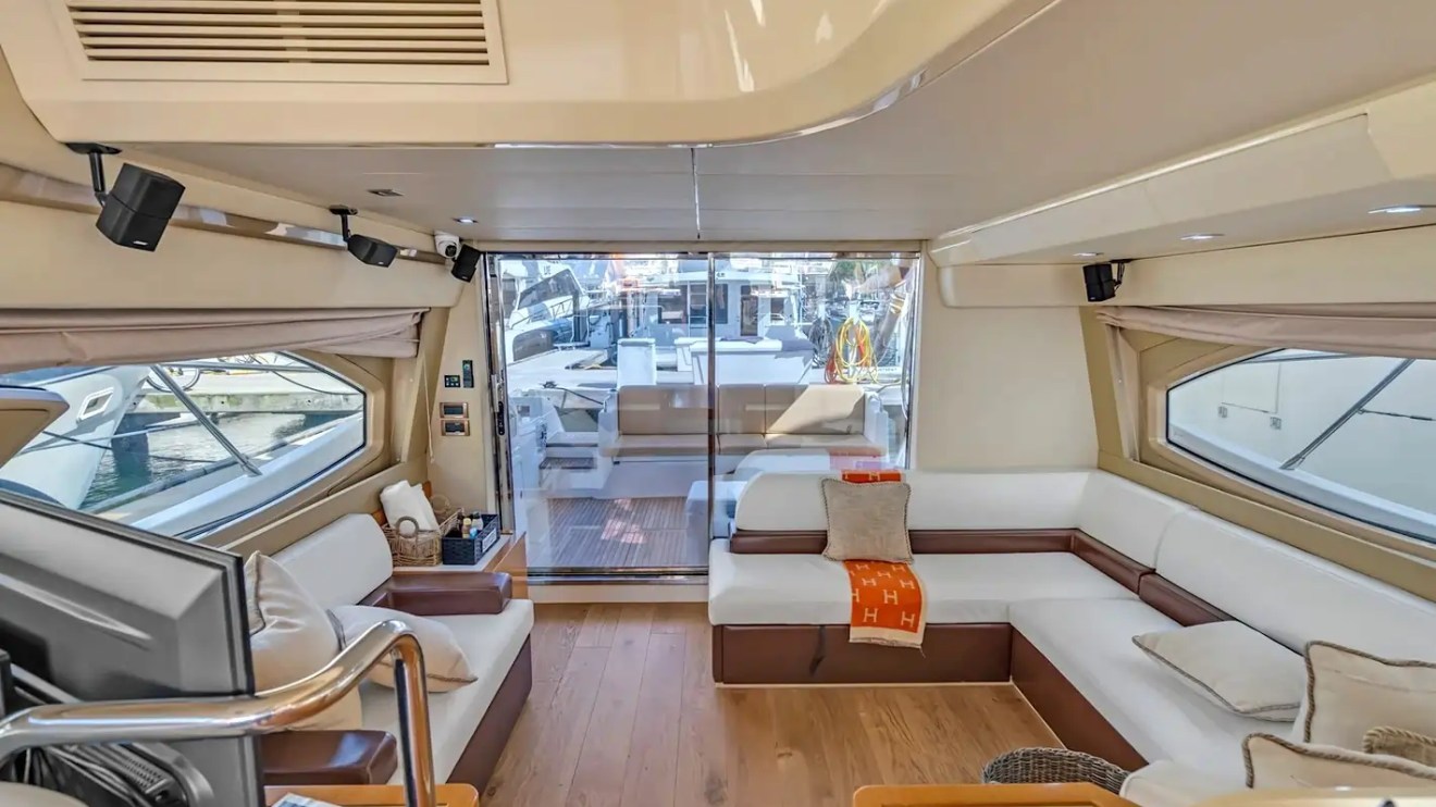 Luxurious yacht interior with white sofas, wood flooring, and glass doors to deck.