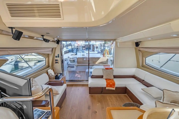 Luxurious yacht interior with white sofas, wood flooring, and glass doors to deck.