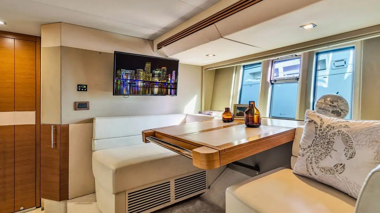 Modern yacht interior with seating, table, decor, and wall-mounted TV.