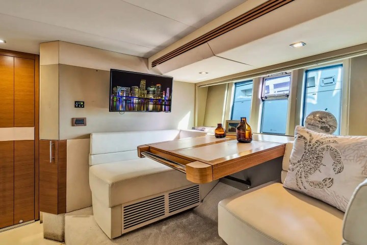 Modern yacht interior with seating, table, decor, and wall-mounted TV.