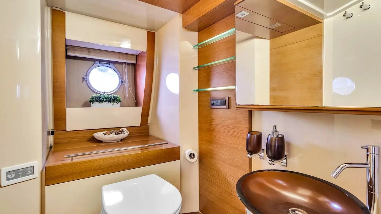 Modern boat bathroom with round sink and window, wooden accents, and decorative plant.