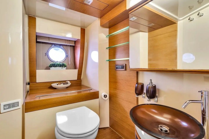 Modern boat bathroom with round sink and window, wooden accents, and decorative plant.