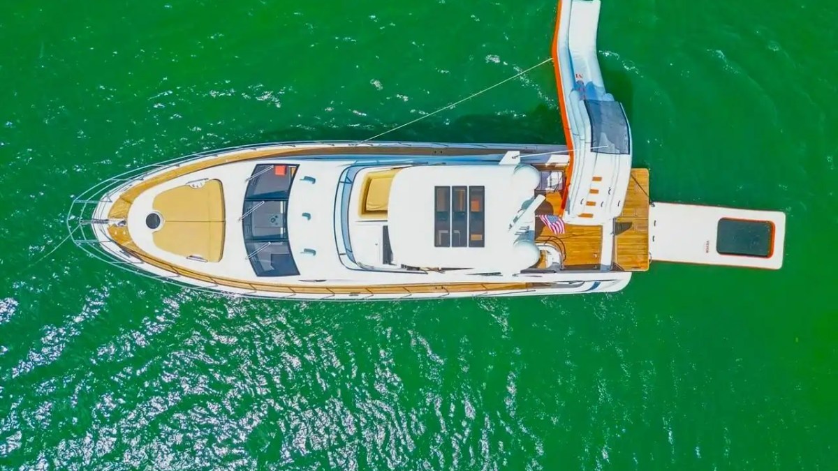 Aerial view of a yacht with a slide in green water.