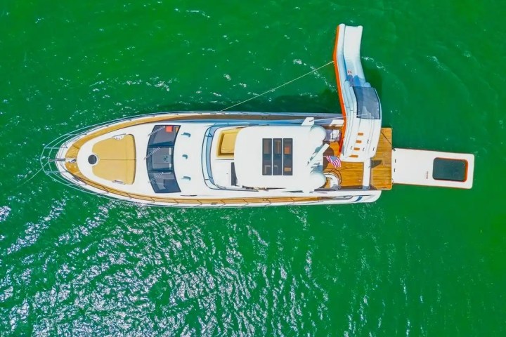 Aerial view of a yacht with a slide in green water.